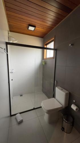 a bathroom with a toilet and a glass shower at Chalé dos Lagos Ecoresort in Mandaguaçu