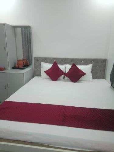 a bedroom with a large white bed with red pillows at CHAYAA BITHII Resort & Restaurant in Kopāi