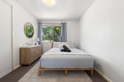 a white bedroom with a bed and a window at Comfortable Home for 6 - Canberra Inner North in Belconnen