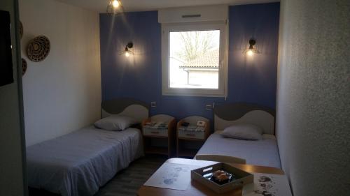 a room with two beds and a table and a window at Les Clés Nature Studio 42 in Moutiers-sous-Chantemerle
