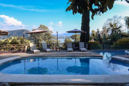 a swimming pool with chairs and umbrellas in a resort at Villas Paraiso Valle de Bravo in Valle de Bravo