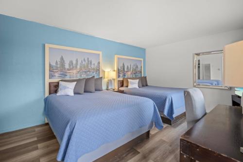 two beds in a hotel room with blue walls at Bluebird Day Inn & Suites in South Lake Tahoe