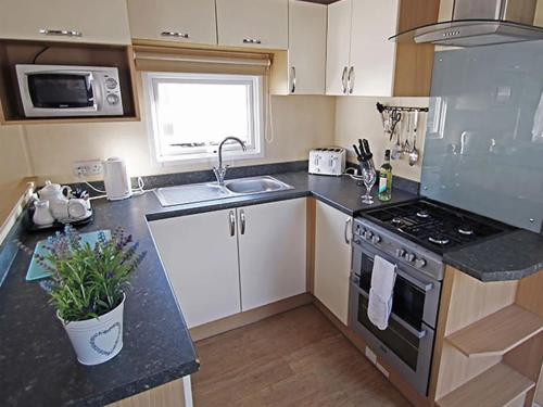 a small kitchen with a stove and a sink at 1. Forest Edge 2 Bedroom Statement Caravan in Saint Leonards