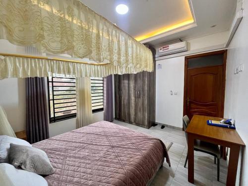 a bedroom with a bed and a desk and a window at Kigali Great Garden in Kigali