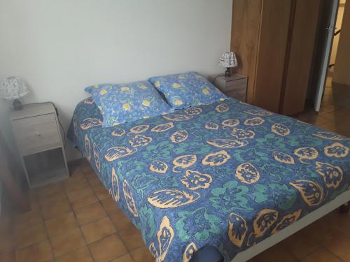 a bedroom with a bed with a blue and gold blanket at Maison au tilleul in Ribiers