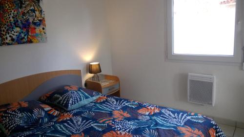 a bedroom with a bed with a blue comforter and a window at Les Clés Nature Apt 44 in Moutiers-sous-Chantemerle