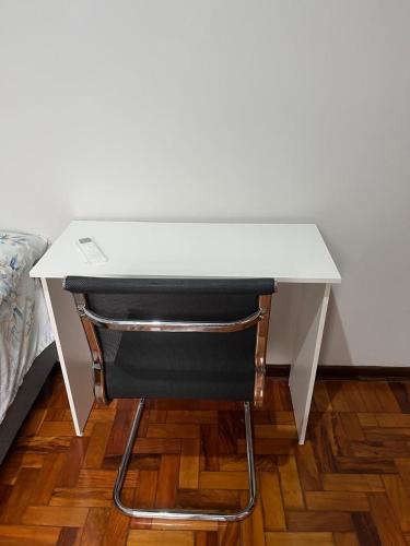 a white desk with a black chair next to a bed at suite privativa centro de Dourados in Dourados