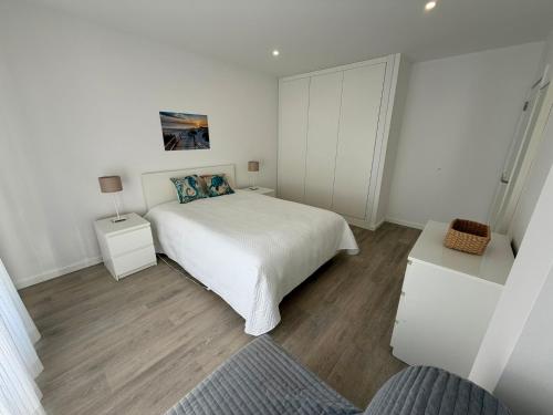 a white bedroom with a bed and two night stands at Altura da Maré - Apartamento Duna in Altura