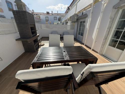 a patio with a wooden table and chairs on a balcony at Altura da Maré - Apartamento Duna in Altura
