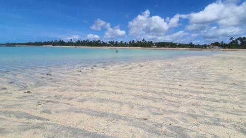 a sandy beach with the water and trees in the background at Casa Centro de Maragogi in Maragogi