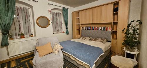 a small bedroom with a bed and a chair at Ferienwohnung am Wald in Tharandt