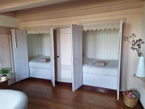 two beds in a room with white walls and wood floors at Logement Alde Leie in Alde Leie