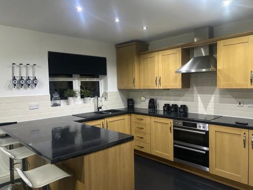 a kitchen with wooden cabinets and a black counter top at Entire 3 bedroom deluxe house in Cleckheaton
