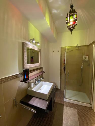 a bathroom with a sink and a shower and a chandelier at Blue Zen beachfront apartment in Civitanova Marche