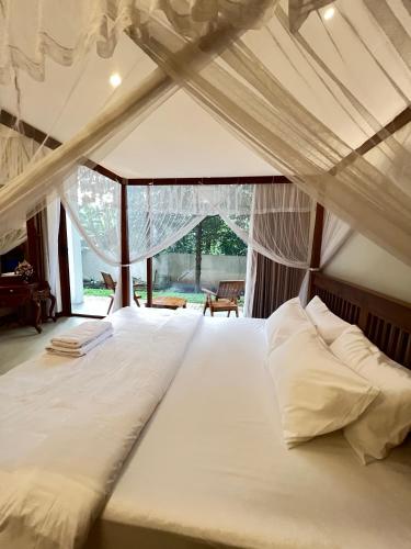 a large white bed in a room with a window at Lumiere Villa, Kandy in Nugawela