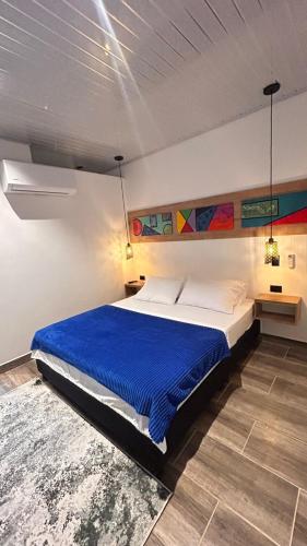 a bedroom with a large bed with a blue blanket at aparta hotel del toro in Estación El Salto
