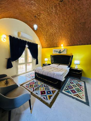 a bedroom with a bed and a yellow wall at Abu simbel Nubian Guest House in Abu Simbel