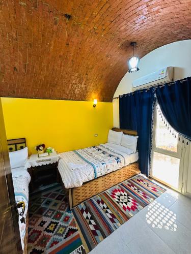 a room with two beds and a yellow wall at Abu simbel Nubian Guest House in Abu Simbel