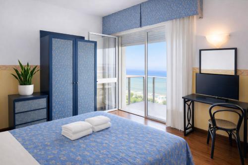 a bedroom with a bed with a desk and a window at Hotel Regina Fronte Mare in Rimini