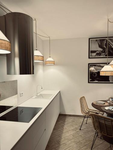 a white kitchen with a sink and a table at Libeccio - Villa Marina in Marina di Andora