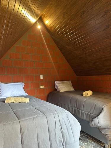 two beds in a room with a brick wall at AndeStay Hostel Colpapampa in Colcapampa
