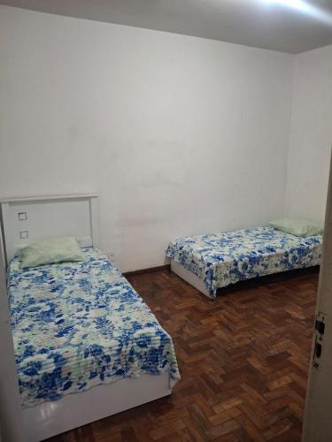 a bedroom with two beds and a wooden floor at Aconchego in Juiz de Fora
