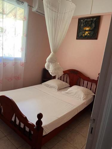 a bedroom with a wooden bed with a canopy at Entre Montagne et Mer in Vieux-Habitants