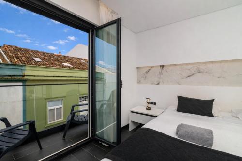 a bedroom with a bed and a large window at The Rock Hostel in Ponta Delgada