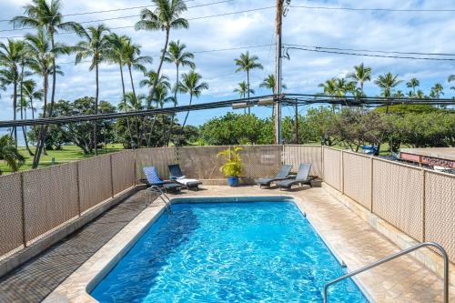 a swimming pool with two lounge chairs next to a fence at Condo with Private Lanai, Ocean View and On-Site Pool! in Kihei