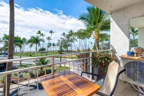 a balcony with a wooden table and chairs and the ocean at Condo with Private Lanai, Ocean View and On-Site Pool! in Kihei