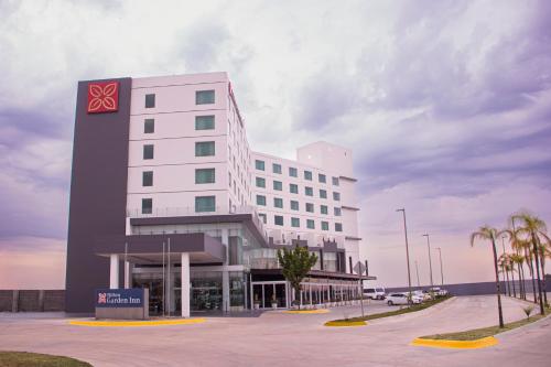a large white building with palm trees in front of it at Hilton Garden Inn Salamanca in Salamanca