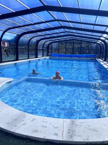 two people swimming in a large swimming pool at Casa Rural Puente del S,egura in Elche de la Sierra