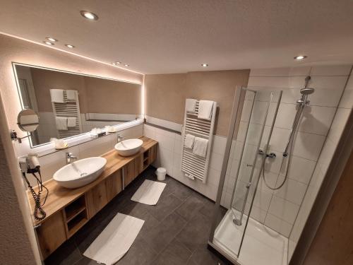 a bathroom with two sinks and a shower at Lobinger Parkhotel & Restaurant in Giengen an der Brenz