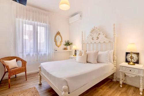 a white bedroom with a white bed and a chair at Caíque - Apartamento de Charme com 3 Quartos no Centro Histórico de Olhão in Olhão