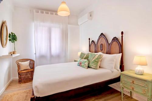 a bedroom with a bed with a wooden headboard and a table at Caíque - Apartamento de Charme com 3 Quartos no Centro Histórico de Olhão in Olhão