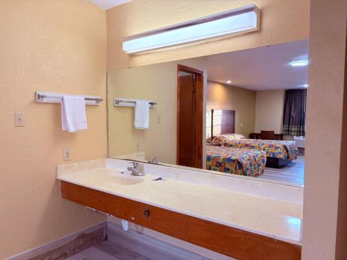 a bathroom with a sink and a mirror and a bed at Aloha Inn McAllen Airport near Medical center Tx in McAllen