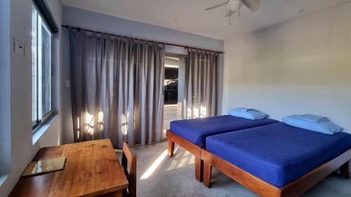 a bedroom with a blue bed and a table at Casa Celeste in Playa Pelada