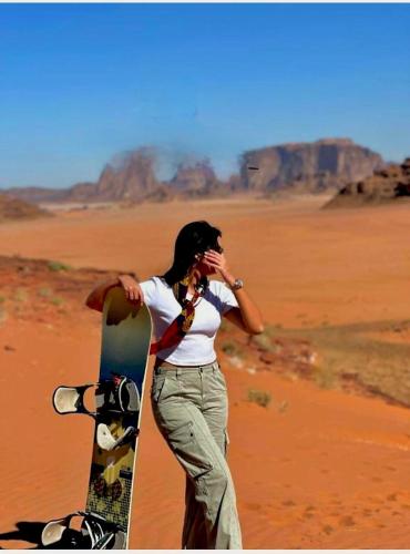 a woman standing in the desert with a skateboard at Taj Wadi Rum camp in Wadi Rum