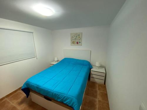 a bedroom with a blue bed in a white room at La Novelera in Echedo