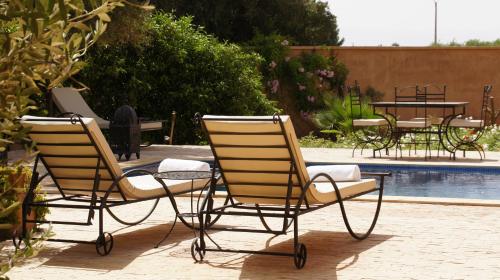 two chairs and a table next to a pool at Riad Jardin des Orangers in Taroudant