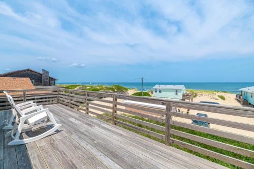 a wooden deck with a chair on the beach at Ocean Wynns - Nags Head MP 13, 20 Yards to the Beach, Ocean Views, Close to Attractions in Nags Head