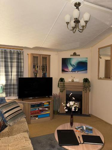 a living room with a couch and a flat screen tv at The West Lakes Caravan in Lamplugh