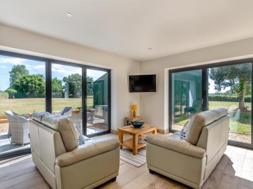 a living room with two chairs and windows at Cathill Cottage in Creech Saint Michael