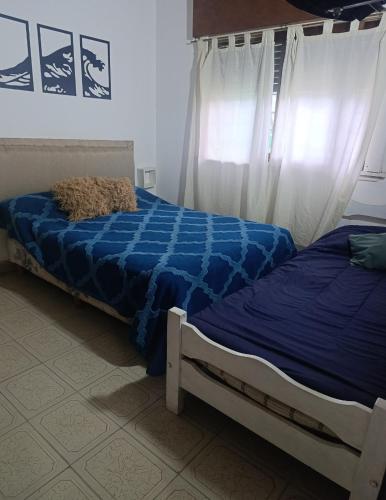 a bedroom with two beds with blue sheets at Nafaro in Villa Gesell