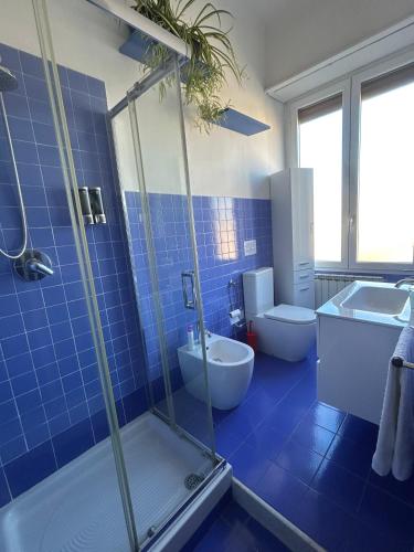 a blue tiled bathroom with a shower and a sink at Interno24 Apartment in La Spezia