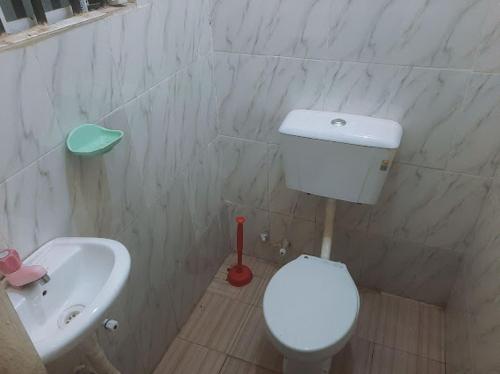 a bathroom with a white toilet and a sink at Crown Dove in Benin City