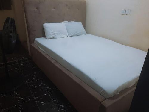 a white bed with two pillows on top of it at Crown Dove in Benin City