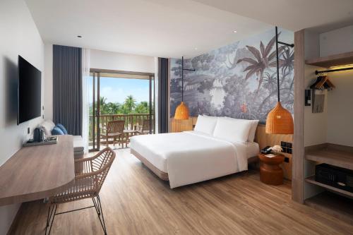 a hotel room with a bed and a table and a desk at Amari Bangsaen in Bangsaen