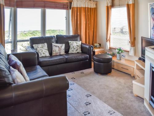 a living room with a leather couch and a television at Sea View in Trimingham