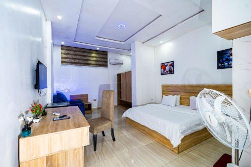a hotel room with a bed and a desk and a table at Frenezia Hotel and Apartment Ikeja GRA in Ikeja